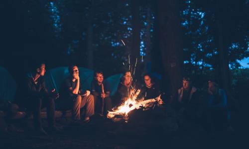 picture of several people sitting around a campfire representing fellowship